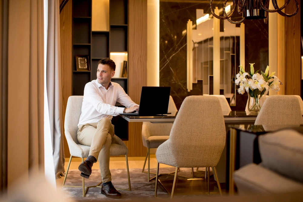 Business man sitting in a luxurious room in front of a laptop