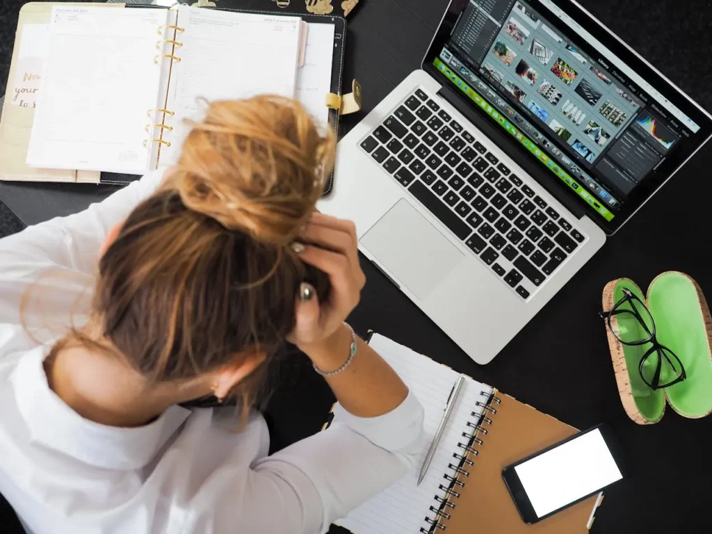 A stressed realtor on the phone while typing on a laptop