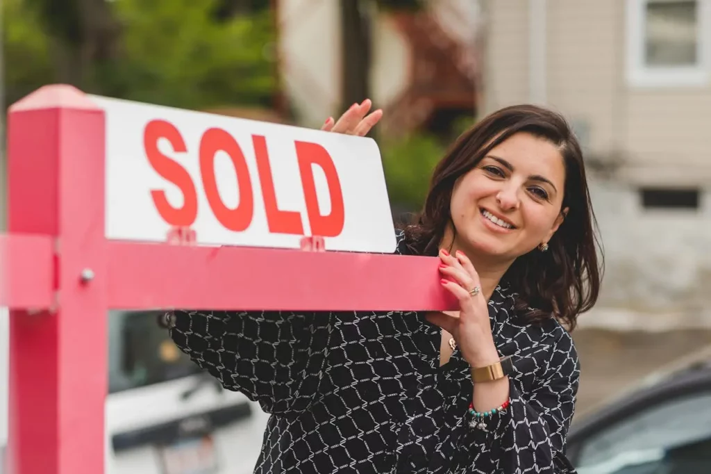 A real estate agent holding a branded "Sold" sign