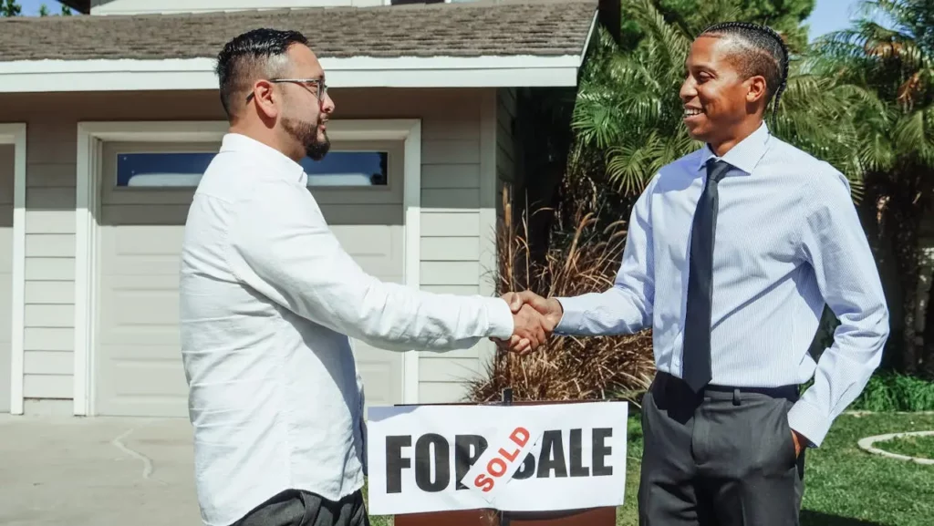 A smiling family in front of their new home with a "sold" sign