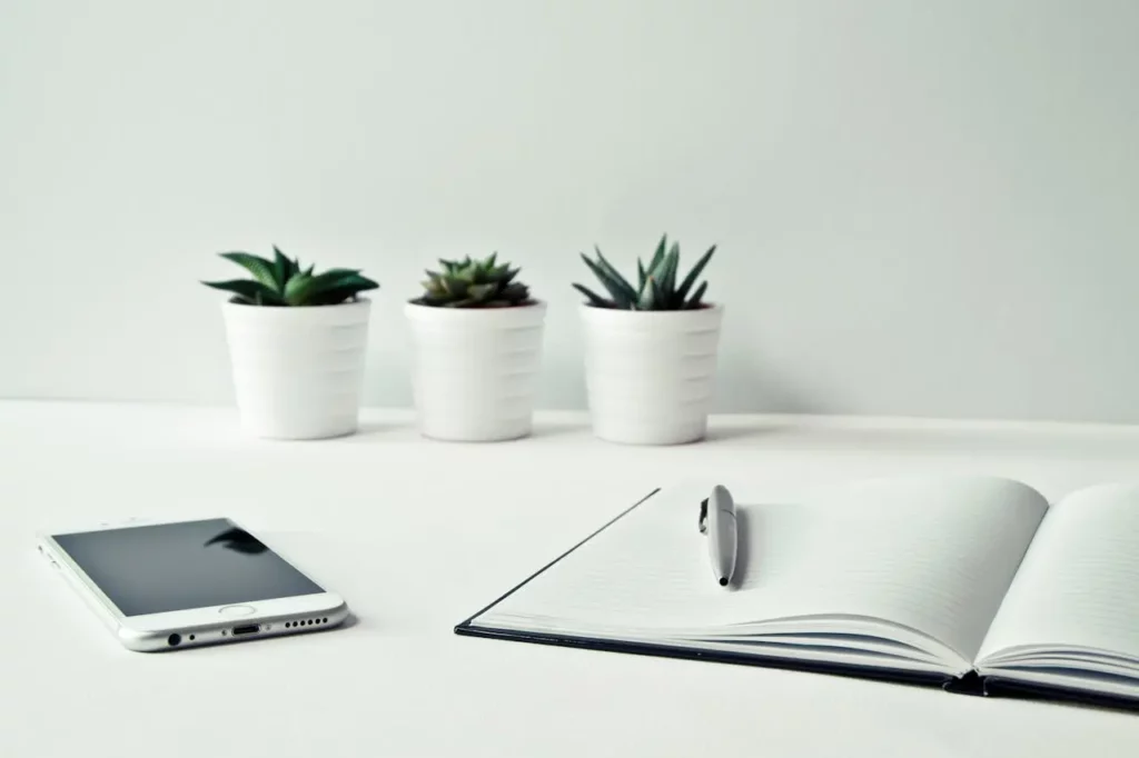 A Realtor’s desk with a phone, laptop, and open notebook for follow-ups