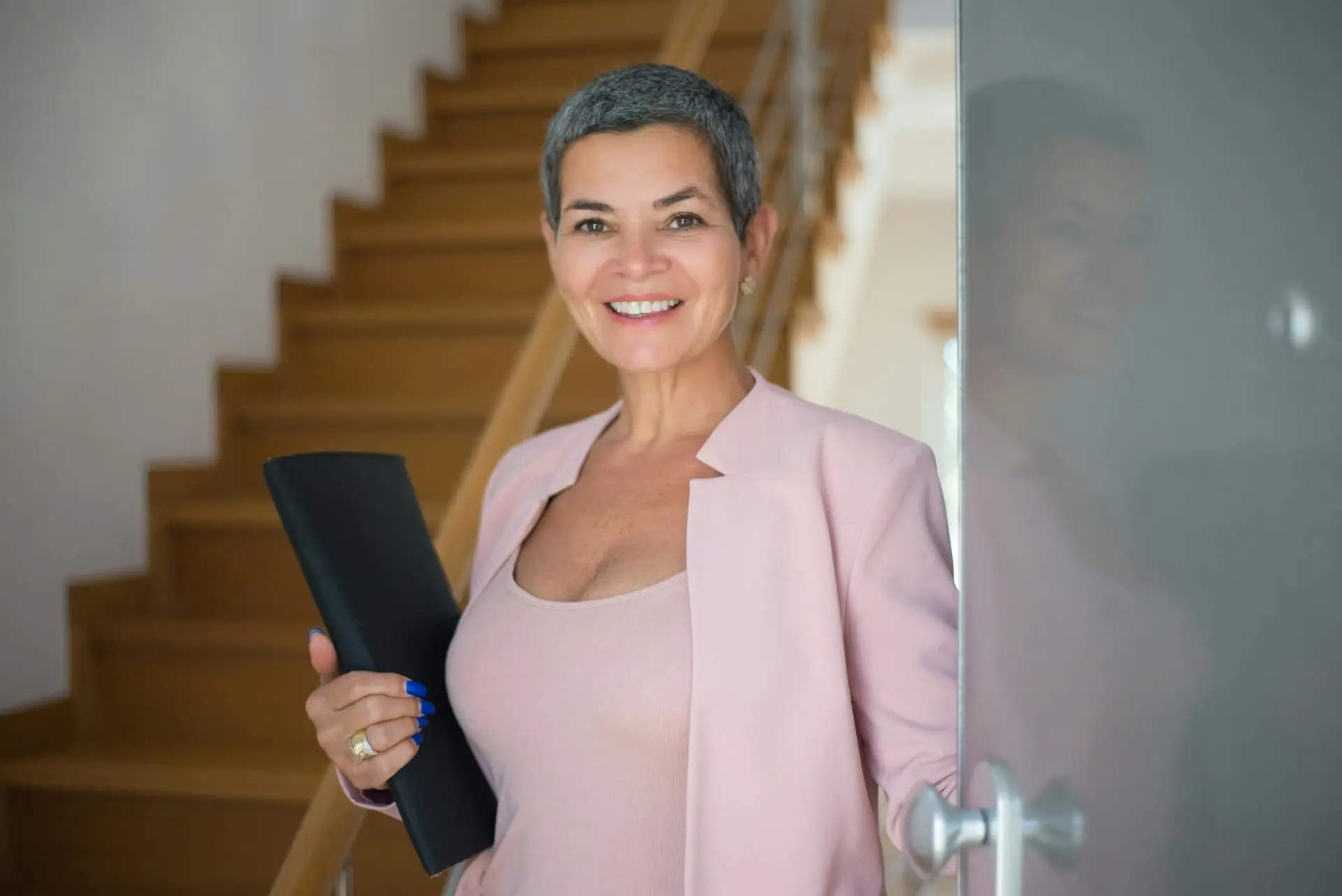 A confident Realtor posing in front of a luxury home.