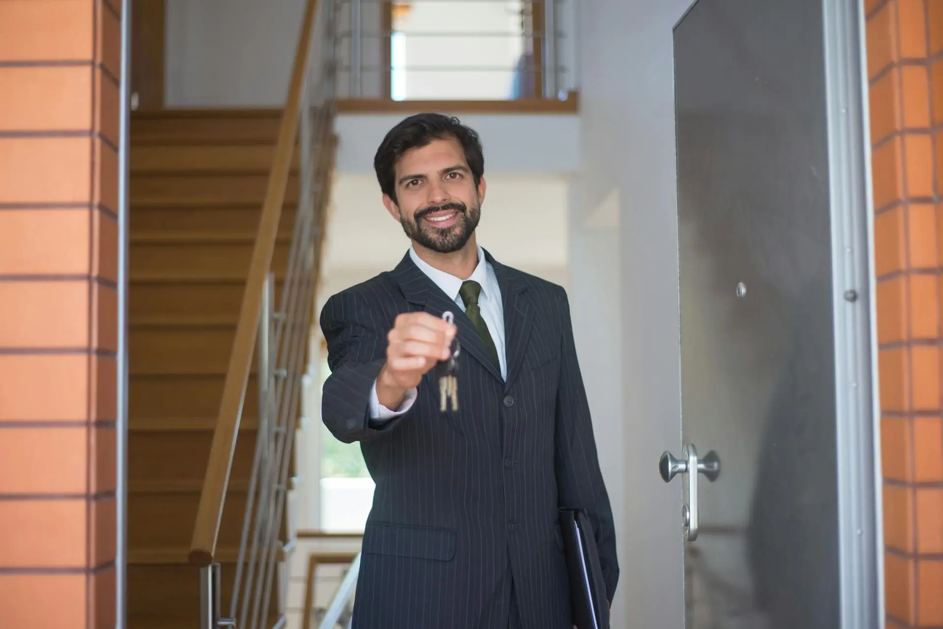 Realtor handing keys to happy homeowners in front of a springtime home.